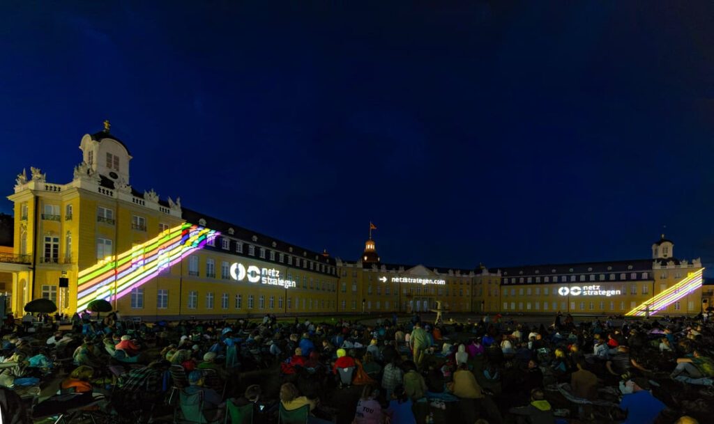 Schlosslichtspiele KarlsruheOpen-Air-Event vor einem beleuchteten Schloss mit Projektionen auf der Fassade, ideal für lokale Werbung und kreative Marketingstrategien.