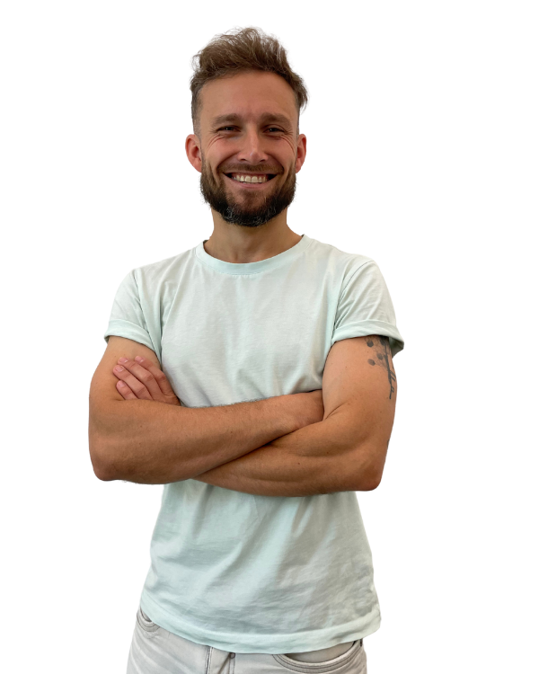 Porträt eines lächelnden Mannes mit Bart, der ein hellblaues T-Shirt trägt und die Arme verschränkt hat. Schwarzer Hintergrund, kurze, braune Haare.